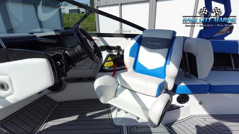 Slide: The Image of 2019 Nautique Super Air Nautique 230 boat interior with blue and white seating. - 18