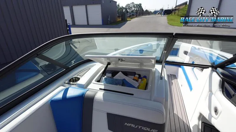 Slide: The Image of 2019 Nautique Super Air Nautique 230 interior with open storage compartment, blue and white seating. - 25