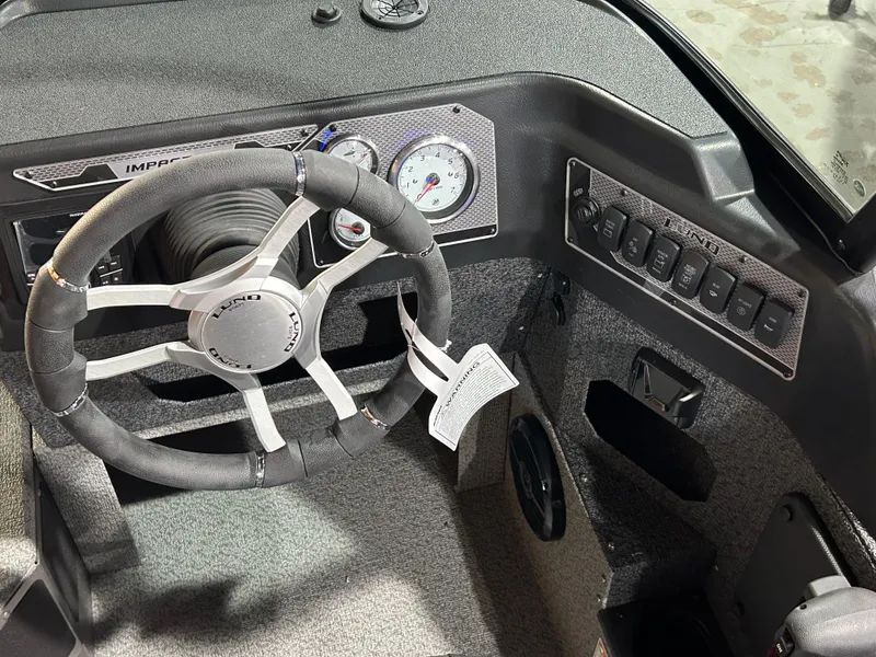 Slide: The Image of 2025 Lund Impact XS 1875 Sport boat dashboard with steering wheel and control panel. - 11