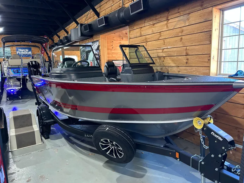 Slide: The Image of 2025 Lund Impact XS 1875 Sport boat in showroom, sleek design, red and gray color scheme. - 2