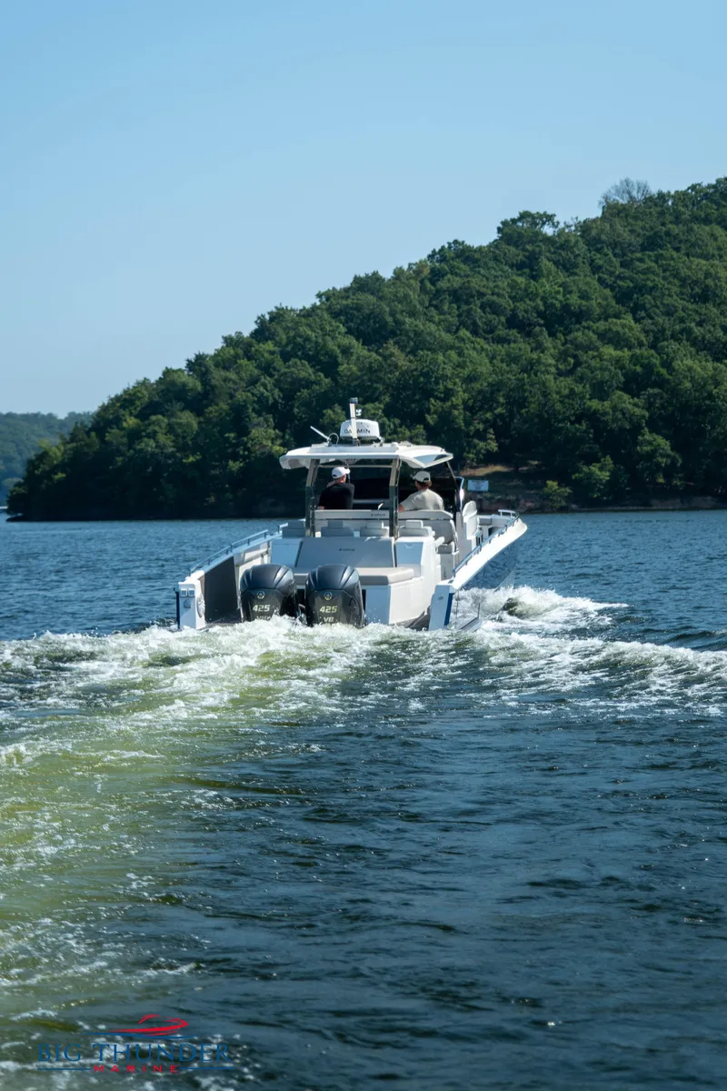 Slide: The Image of Opus 12 boat 2024 cruising on a lake with wooded shores. - 20