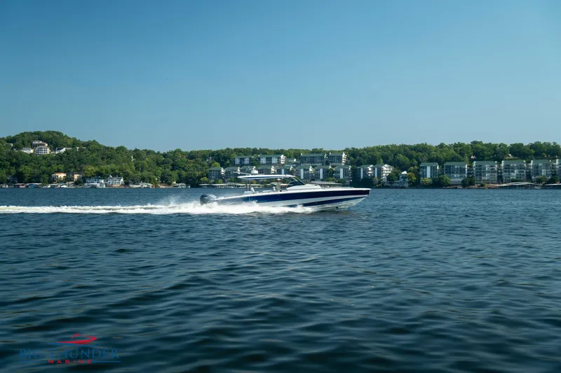 Slide: The Image of Opus 12 boat 2024 cruising on a serene lake with wooded shoreline. - 5
