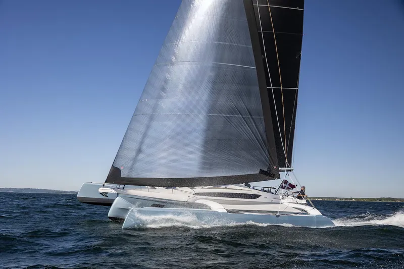 Slide: The Image of Sleek 2027 Dragonfly 36 trimaran sailing on open water under clear blue skies. - 2