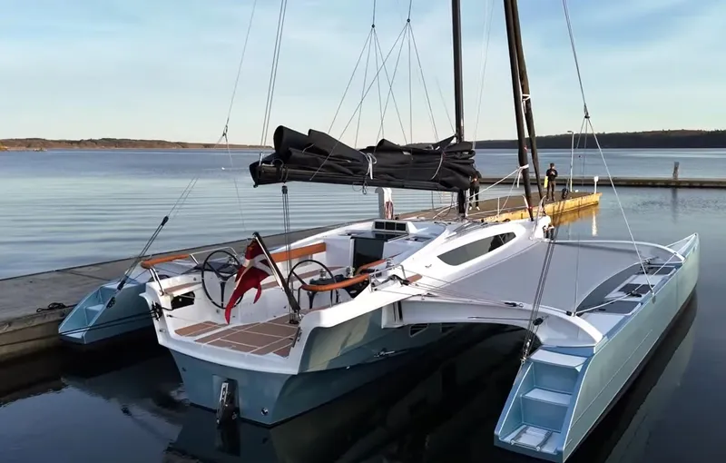 Slide: The Image of 2027 Dragonfly 36 trimaran docked on calm water, featuring sleek design and modern sails. - 6