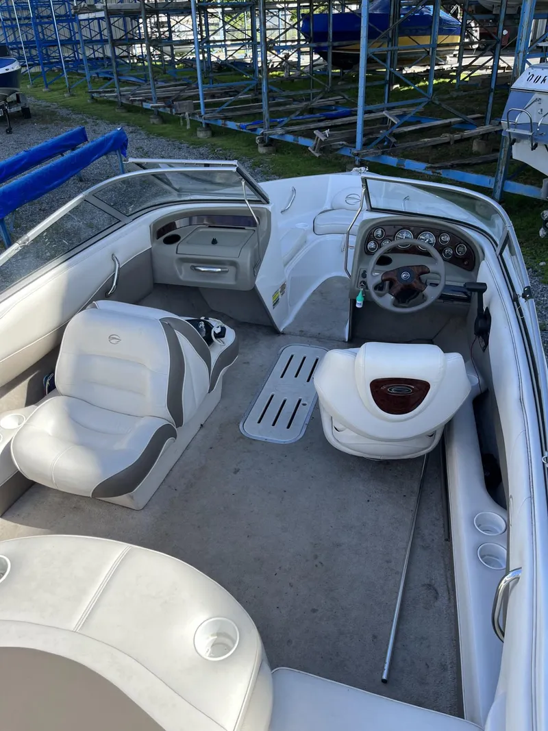 Slide: The Image of 2005 Crownline 180 BR boat interior with seating and dashboard, parked in storage area. - 9