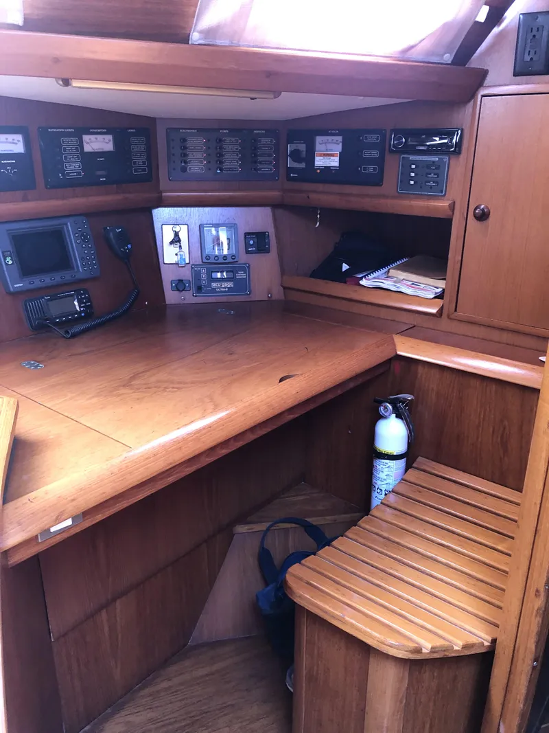 Slide: The Image of Navigation station of 2001 Jeanneau 45.2 sailboat with wooden desk and control panels. - 12