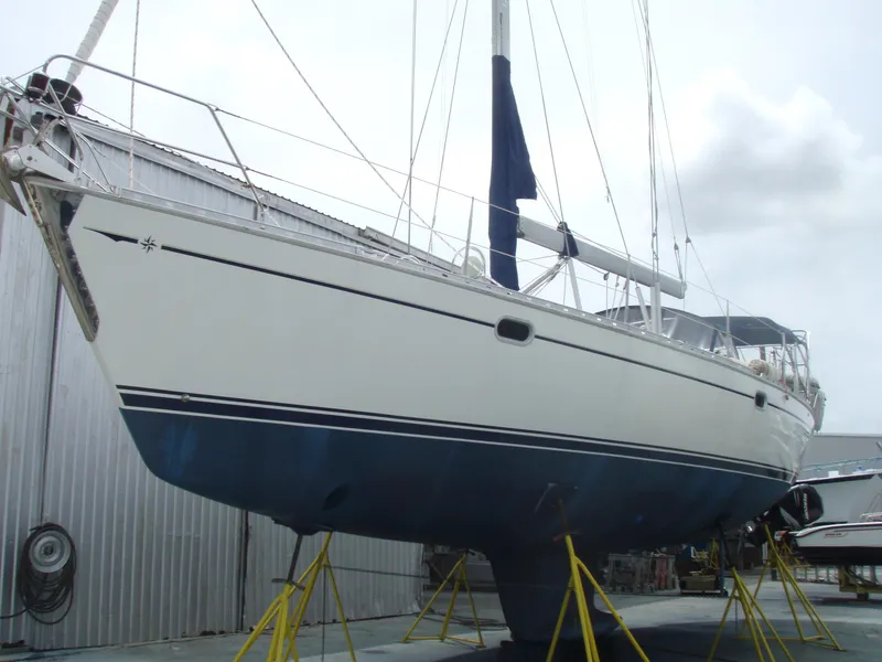 Slide: The Image of 2001 Jeanneau 45.2 sailboat on stands, white hull, blue bottom, in a boatyard. - 24