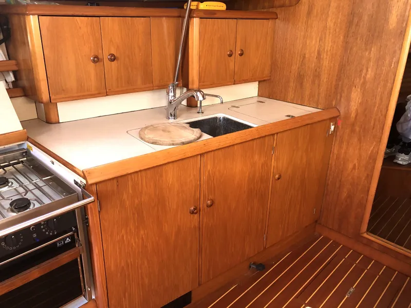 Slide: The Image of 2001 Jeanneau 45.2 yacht kitchen with wooden cabinets and sink. - 9