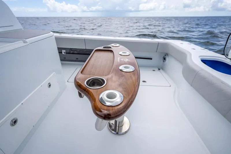 Slide: The Image of 2023 Freeman 43 boat with sleek wooden fishing station, cup holders, and ocean backdrop. - 44