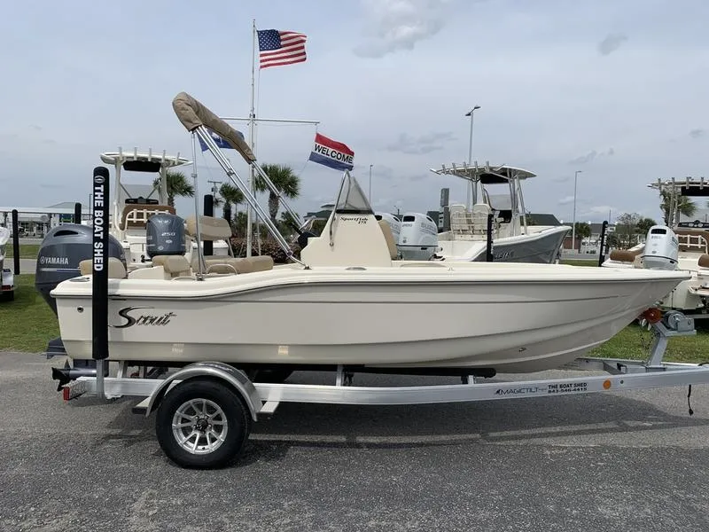 Slide: The Image of 2025 Scout 175 Sportfish boat on trailer, displayed outdoors with flags in the background. - 4