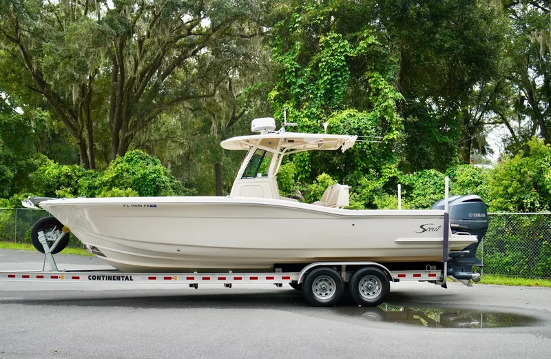Slide: The Image of 2009 Scout 282 Sportfish boat on trailer, surrounded by lush greenery. - 1