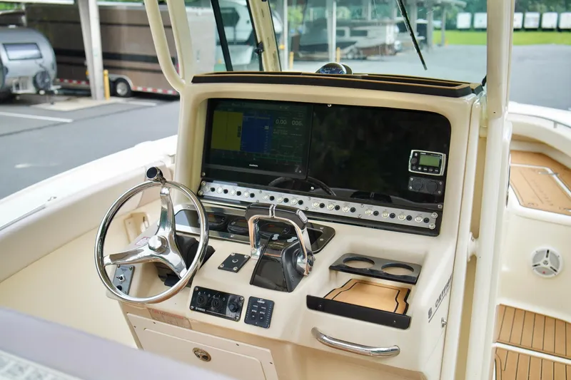 Slide: The Image of 2009 Scout 282 Sportfish boat dashboard with steering wheel and navigation controls. - 14