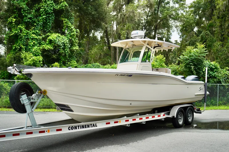 Slide: The Image of 2009 Scout 282 Sportfish boat on trailer, surrounded by lush greenery. - 5