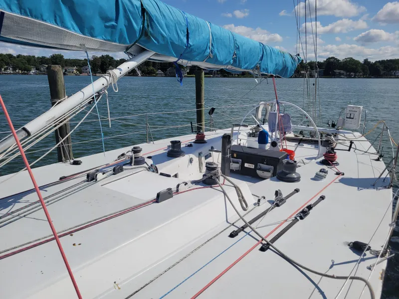 Slide: The Image of 1990 Nelson Marek IOR 50 racing sailboat with blue sail cover, docked on calm water. - 7