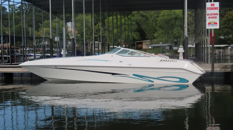 The Image of 1997 Envision Intruder 3200 boat docked on calm water under a covered marina. - 0