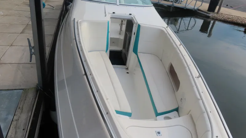 Slide: The Image of 1997 Envision Intruder 3200 boat docked, featuring spacious white seating with teal accents. - 4