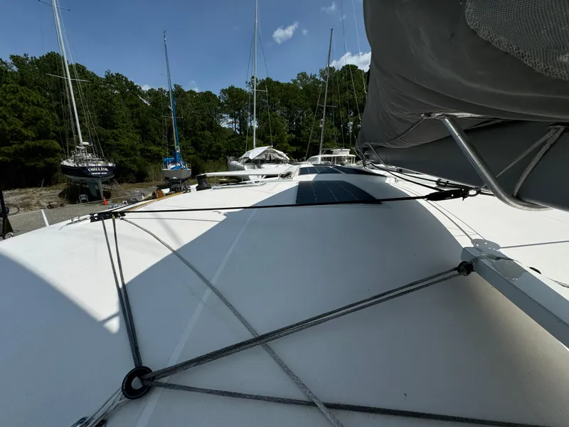 Slide: The Image of 2010 Outremer 49 sailboat deck with rigging, docked near trees and other boats. - 27