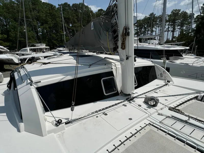 Slide: The Image of Outremer 49 catamaran, 2010 model, docked with sails down, surrounded by trees and other boats. - 28