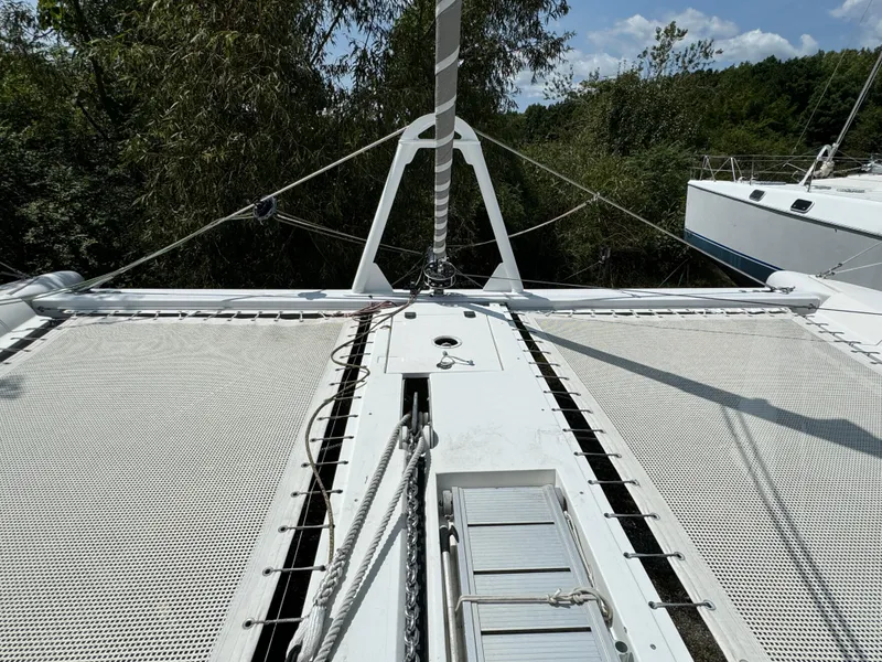 Slide: The Image of Outremer 49 catamaran deck with rigging, 2010 model, surrounded by lush greenery. - 32