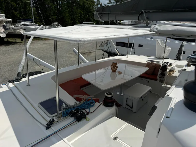 Slide: The Image of 2010 Outremer 49 catamaran cockpit with canopy, seating, and table, docked outdoors. - 38