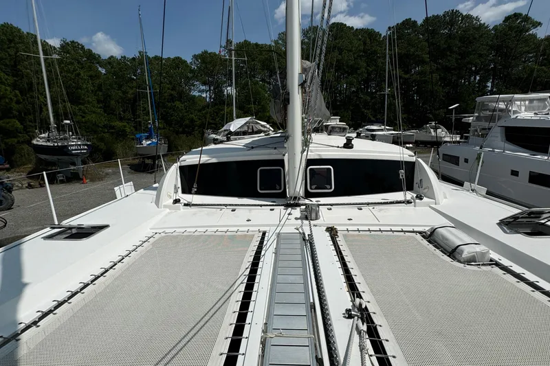 Slide: The Image of Outremer 49 catamaran, 2010 model, docked with visible netting and mast, surrounded by trees. - 44
