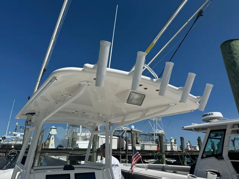 Slide: The Image of 2009 Regulator 32 Forward Seating boat at marina, featuring rod holders and clear blue sky. - 48
