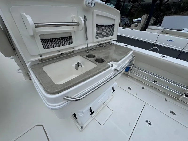 Slide: The Image of Boston Whaler 330 Outrage 2022 boat interior with sink and storage area. - 14
