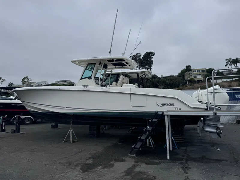 Slide: The Image of 2022 Boston Whaler 330 Outrage boat on display in a marina setting. - 2
