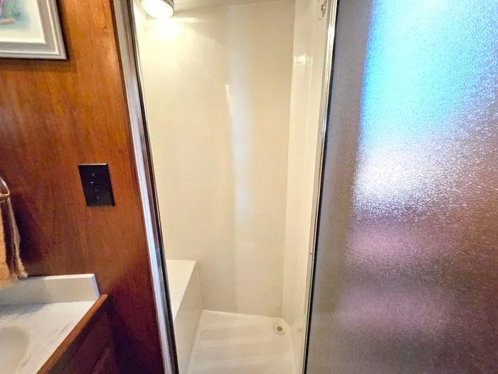 Slide: The Image of Shower area in a 1993 Navigator 4300 boat with wooden accents and frosted glass door. - 27
