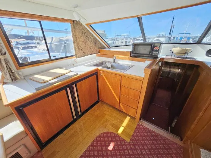 Slide: The Image of Navigator 4300 yacht kitchen interior, featuring wood cabinetry, sink, and microwave, 1993 model. - 9