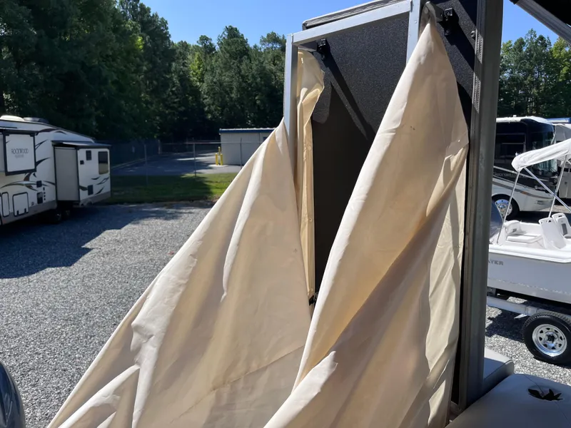 Slide: The Image of 2021 Bennington SV 20 Quad Bench with beige cover in outdoor storage area. - 14