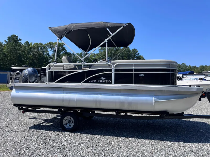 Slide: The Image of 2021 Bennington SV 20 Quad Bench pontoon boat on trailer, black canopy, sunny day. - 19