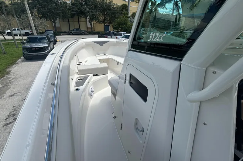 Slide: The Image of 2025 Sailfish 312 CC boat, sleek white deck, modern design, parked outdoors. - 17