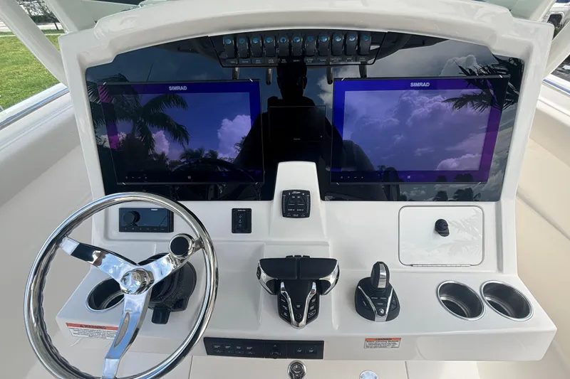 Slide: The Image of 2025 Sailfish 312 CC boat dashboard with dual Simrad displays and steering wheel. - 24