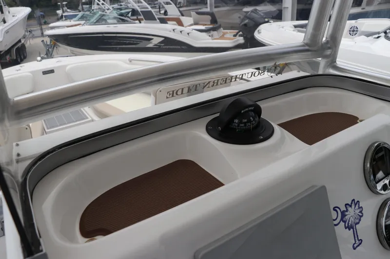 Slide: The Image of 2018 Robalo R202 Explorer boat dashboard with compass, docked among other boats. - 4