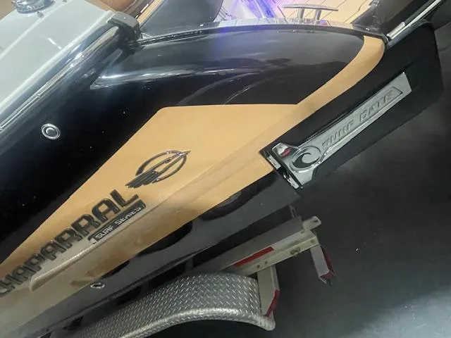 Slide: The Image of 2025 Chaparral 30 Surf boat on trailer, featuring sleek black and tan design. - 5