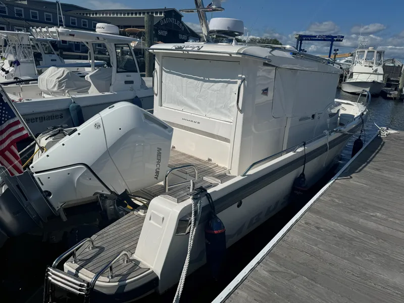 Slide: The Image of 2024 Nimbus Commuter 9 boat docked at marina, featuring sleek design and modern outboard motor. - 2