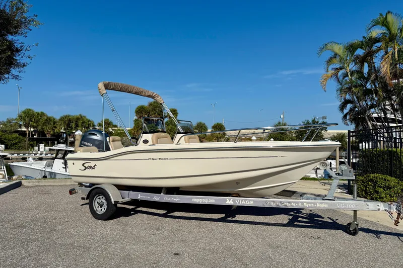 Slide: The Image of 2024 Scout 175 Sport Dorado boat on trailer, parked outdoors under clear blue sky. - 1