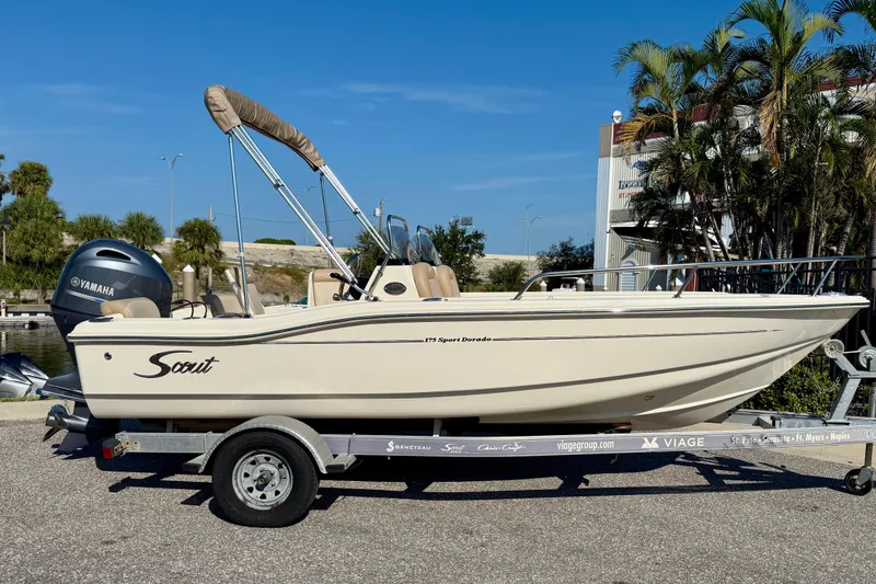 Slide: The Image of 2024 Scout 175 Sport Dorado boat on trailer, featuring Yamaha engine, parked outdoors. - 2