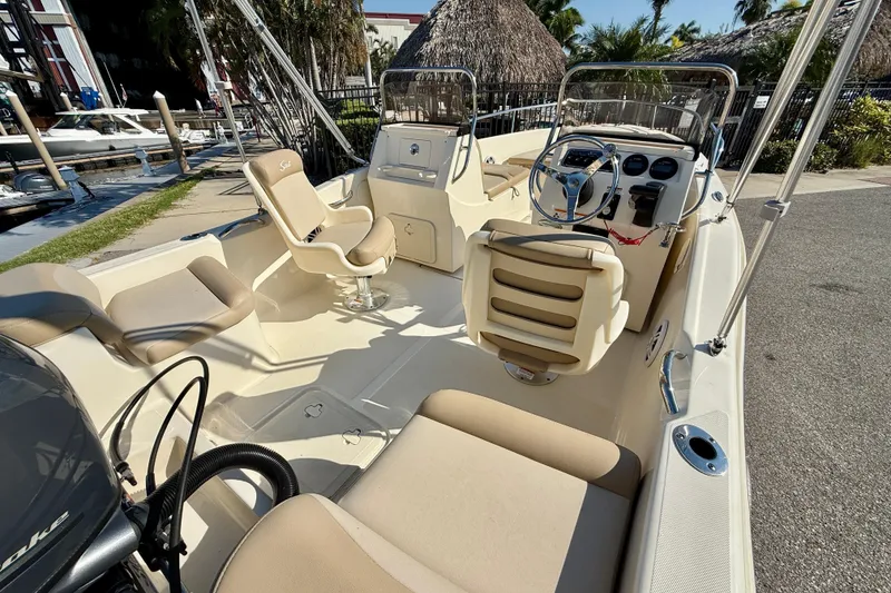 Slide: The Image of 2024 Scout 175 Sport Dorado boat interior with seating and steering wheel, dockside view. - 5
