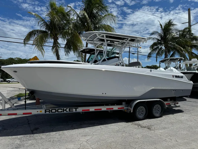 The Image of 2024 Wellcraft 262 Fisherman boat on trailer, parked near palm trees under a blue sky. - 1