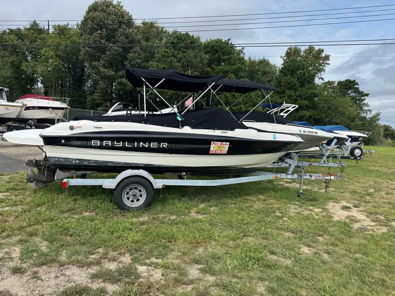 Slide: The Image of 2011 Bayliner 185 boat on trailer, parked on grass, with trees in the background. - 1