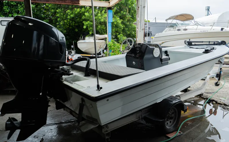 Slide: The Image of 1988 Baretta Success 185 boat on trailer, with outboard motor, in a marina setting. - 10