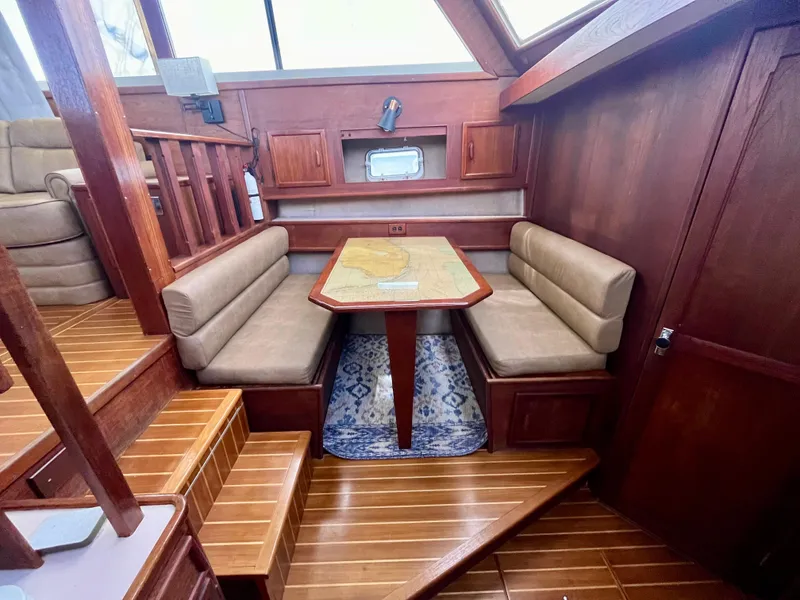 Slide: The Image of 1988 Jersey Dawn 40 yacht interior with wooden dining area and cushioned seating. - 25