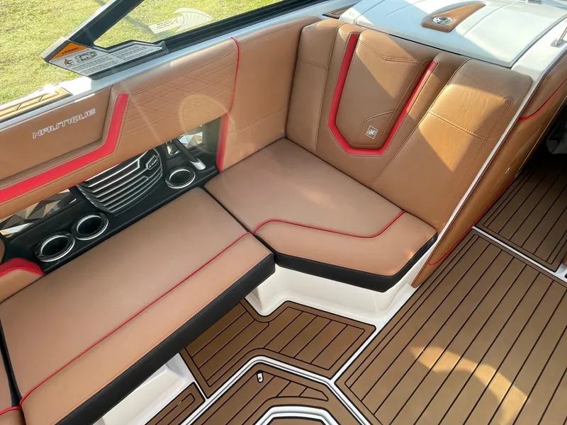 Slide: The Image of 2019 Nautique Super Air Nautique G25 interior with tan and red seating, wood-style flooring. - 10