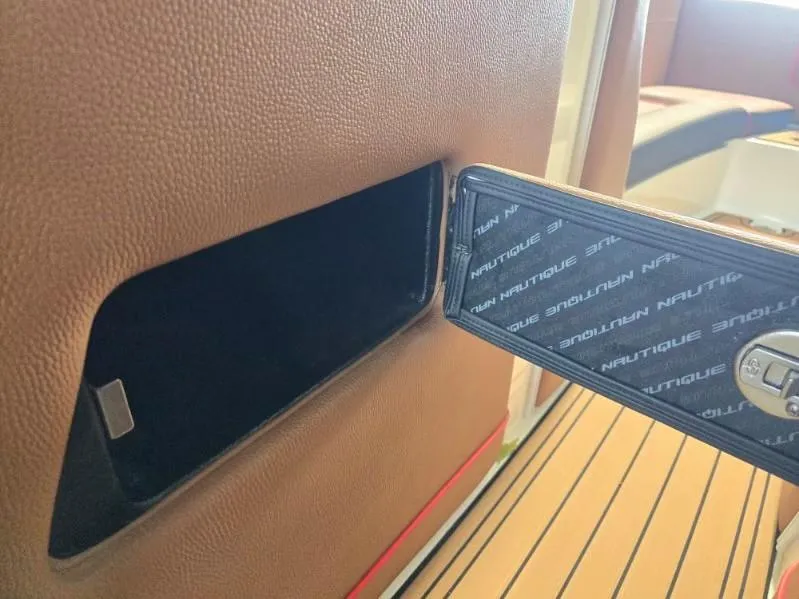 Slide: The Image of 2019 Nautique Super Air Nautique G25 interior detail with branded panel and storage compartment. - 15