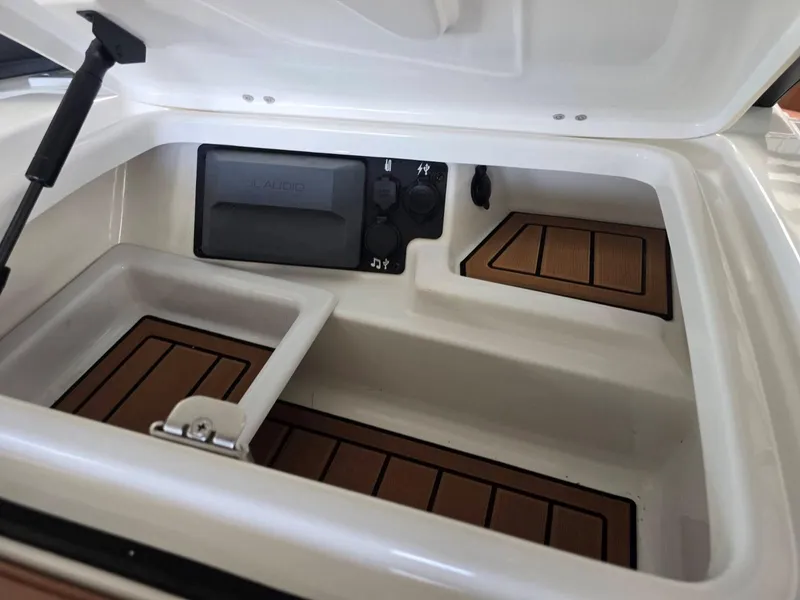 Slide: The Image of 2019 Nautique Super Air Nautique G25 storage compartment with teak flooring and control panel. - 19
