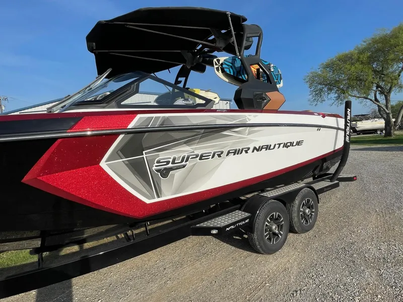 Slide: The Image of 2019 Nautique Super Air Nautique G25 boat on trailer, red and white design. - 2