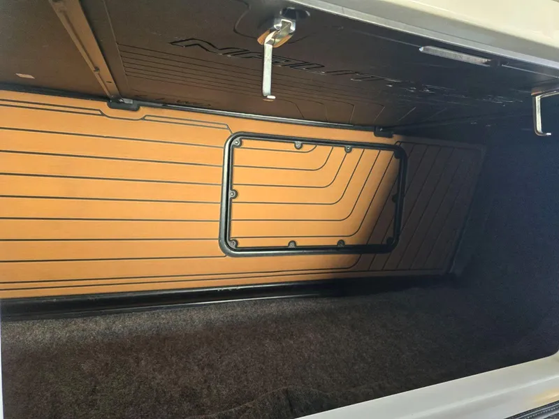 Slide: The Image of 2019 Nautique Super Air Nautique G25 storage compartment with teak flooring and secure latch. - 24