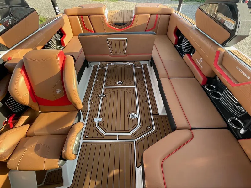 Slide: The Image of 2019 Nautique Super Air Nautique G25 interior with tan and red seating, teak flooring. - 8